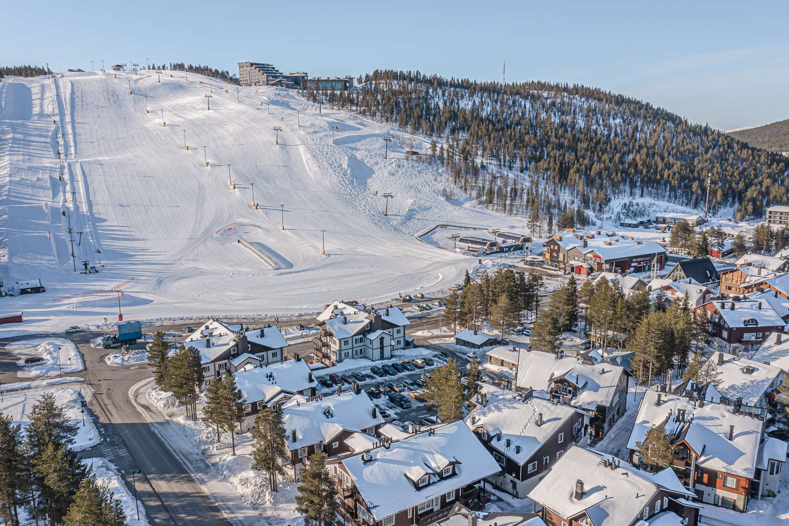 Aerial view of Levi Alpine Chalets with Levi's front ski slopes in the background during winter in Finnish Lapland.